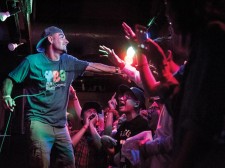 Thes One holds the mic out for the crowd to chant along with the music.