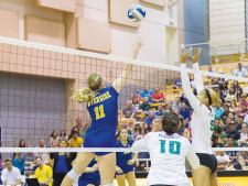 Leslie Pease (no. 11) jumps up to return the ball over the net.