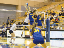 Alex Gresham (No. 6) and Chelsea Doyle (No. 29) reach up to block the ball.