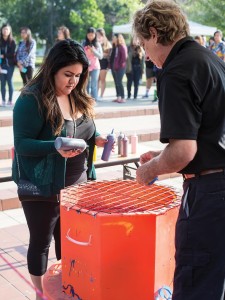 A student using a spinning-top machine to decorate her t-shirt design